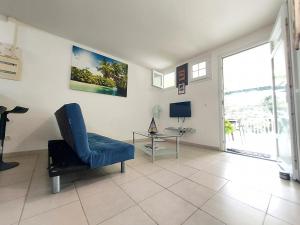 a living room with a blue chair and a table at La créola BAYALOCATION in Rivière-Pilote