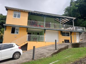 a white car parked in front of a yellow house at La créola BAYALOCATION in Rivière-Pilote