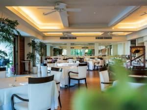 a dining room with white tables and chairs at The Atta Terrace Club Towers in Onna
