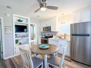 a kitchen with a table and a stainless steel refrigerator at North Cape- Behing Trading Post - Pet Friendly in Cape San Blas