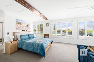 a bedroom with a bed and some windows at La Dolce Vita - Your next coastal getaway in Caves Beach