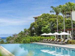 a swimming pool with lounge chairs and umbrellas at The Atta Terrace Club Towers in Onna