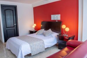 a bedroom with a bed and a red wall at Hotel Victoria in Chinchiná +21 photos