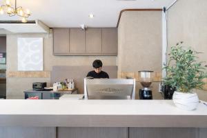 a man sitting in front of a laptop computer in a kitchen at Quicky Stay Hotel Suphanburi in Suphan Buri