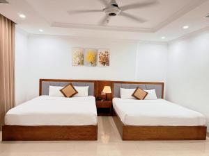 two beds in a room with white walls at Kiwi Beachside Hotel & Cafe Da Nang in Danang