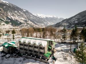 a building in the snow with mountains in the background at Nivasana Manali - A Luxury Boutique Hotel in Manāli
