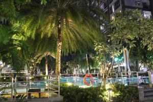 a pool with palm trees in a city at night at Elysian Suites In Landmark Saigon by VNS in Ho Chi Minh City