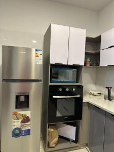a kitchen with a stainless steel refrigerator with a microwave at Departamento de lujo domotizado en la mejor zona de Cochabamba, frente al Paseo Aranjuez in Cochabamba