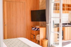 a bedroom with a bed and a tv and a desk at Subu Utamas Villas in Ubud