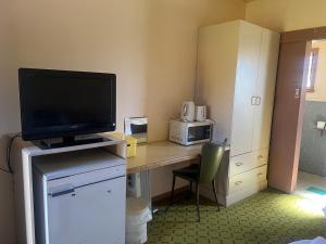a room with a desk with a television and a microwave at Walla Walla Hotel Motel in Walla-Walla