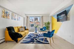 a living room with a yellow couch and blue chairs at 17th Ave Cozy Place in DT, short walk to Calgary Stampede in Calgary