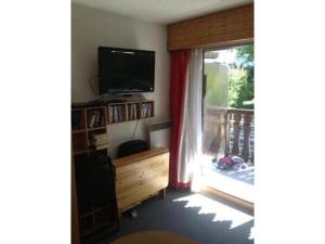 a living room with a television and a window at Apartment Clos du Savoy in Chamonix-Mont-Blanc
