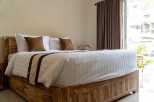 a bedroom with a wooden bed with white sheets and pillows at Danas Pandawa Homestay in Nusa Dua +19 photos