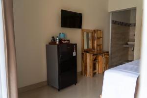 a room with a black refrigerator and a television at Danas Pandawa Homestay in Nusa Dua
