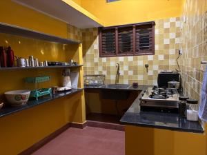 a kitchen with a stove and a yellow wall at Untitled Space Residency in Bangalore