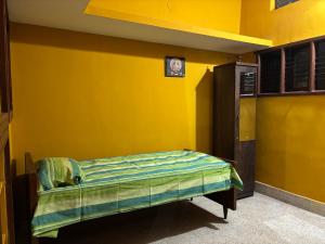 a room with a bed in a yellow wall at Untitled Space Residency in Bangalore