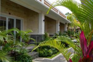 a house with palm trees in front of it at Danas Pandawa Homestay in Nusa Dua