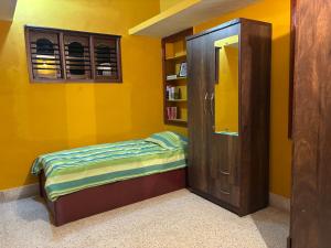 a yellow room with a bed and a book shelf at Untitled Space Residency in Bangalore