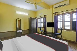 a bedroom with a bed and a desk and a tv at Collection O EXPRESS SUITES in Calicut