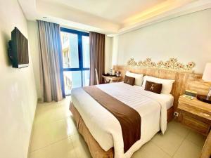 a hotel room with a large bed and a window at Horison Kuta Bali in Kuta