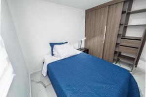 a bedroom with a bed with a blue blanket at Galería 305 in Cartago