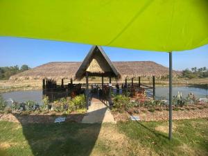 a building with a roof with plants in front of a lake at Isaan Country Retreat in Mukdahan