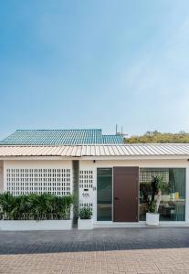a white building with a brown door and some plants at SOL HOUSE kohlarn in Ko Larn