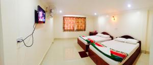 Cette chambre dispose de 2 lits et d'une télévision murale. dans l'établissement The Blue Guest House, à Battambang