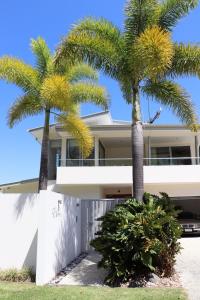 a house with two palm trees in front of it at Luxury House steps from Mooloolaba Beach in Mooloolaba