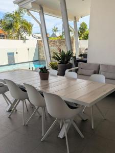 a wooden table and chairs in a room with a pool at Luxury House steps from Mooloolaba Beach in Mooloolaba