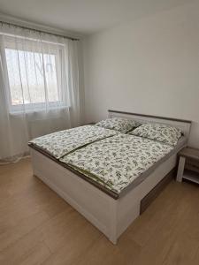 a bed in a white bedroom with a window at Lima Apartment in Bernolákovo