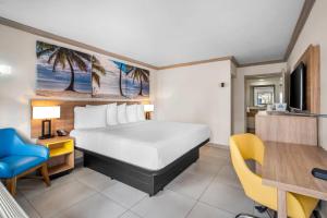 a hotel room with a bed and a desk and a chair at Days Inn by Wyndham Florida City in Florida City