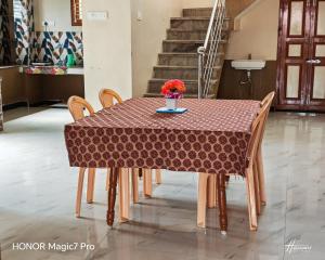 a table with chairs and a vase of flowers on it at ARMANI Villa Nagapattinam in Sikkil
