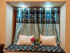 a bed with a blue curtain and a vase with flowers at ARMANI Villa Nagapattinam in Sikkil