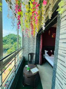 a room with a balcony with a table and flowers at Hotel Nisha in Mahabaleshwar