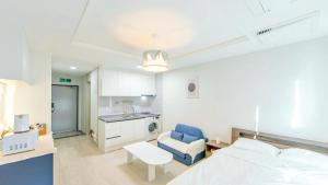 a bedroom with a bed and a chair and a kitchen at Busan Ieumjae Seomyeon Station in Busan