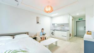 a woman sitting in a chair in a bedroom at Busan Ieumjae Seomyeon Station in Busan