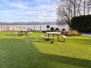 a group of picnic tables on the grass near the water at Przystań NADOLE- APARTAMENT in Nadole