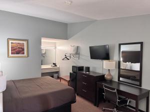 a hotel room with a bed and a desk with a mirror at Owensville Inn in Owensville