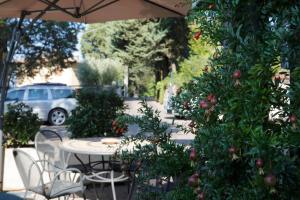a table and chairs under an umbrella with an apple tree at Hotel Porta Nuova in Assisi +44 photos