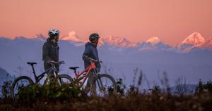 two people with bikes on a hill with mountains in the background at Hotel Himalayan Vista in Pāti Bhanjyāng