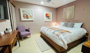 a bedroom with a large bed and a purple chair at Casa Mercedes in Valladolid