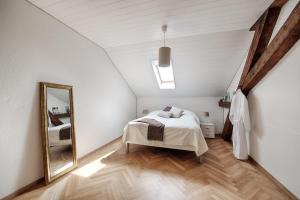 a white bedroom with a bed and a mirror at Am Pavillon Bed & Kitchen in Bern +19 photos