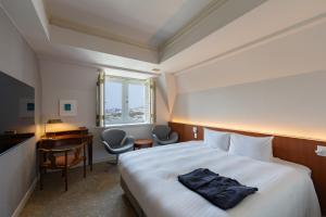 a hotel room with a bed and a desk and a window at Setre Glover's House Nagasaki in Nagasaki