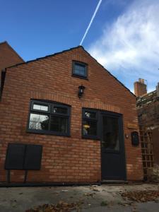 a brick building with a black door and windows at The Stables at the Old Vicarage in Lincoln