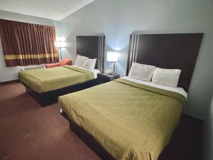 a hotel room with two beds and a chair at Owensville Inn in Owensville
