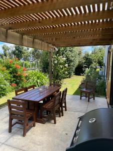 a wooden table and chairs under a wooden pergola at Villa in the Vines in Martinborough