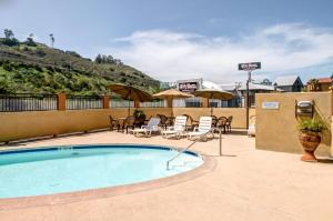 a swimming pool with chairs and tables and umbrellas at Rodeway Inn San Diego Near SDSU in San Diego