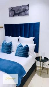 a bed with blue and white pillows on it at Fourways Executive Residence in Four Ways +139 photos
