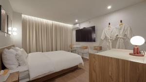a hotel room with a white bed and a clothes rack at Maison de Centum Busan in Busan